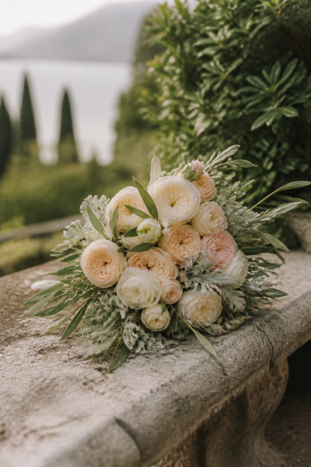 The bridal bouquet of garden roses resting on a stone bench.
